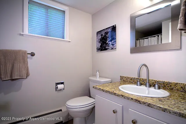 a bathroom with a granite countertop toilet sink and mirror