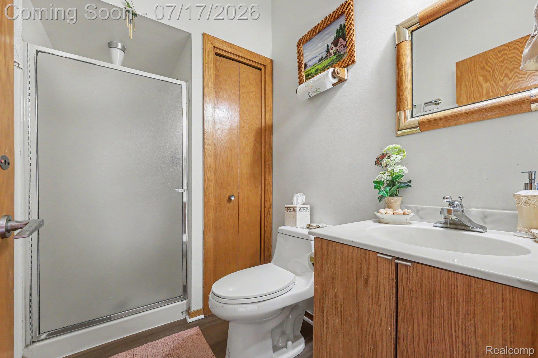5685 Paint Valley Drive Rochester, MI 48306 - Photo 17 of 66 Bathroom featuring a frosted glass shower enclosure, wood-finish vanity with an integrated sink, and a framed wall mirror