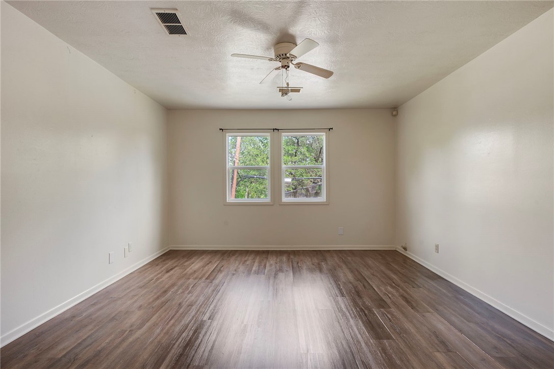 400 Robertson Street Bryan, TX 77803 - Photo 6 of 9 an empty room with wooden floor chandelier fan and windows