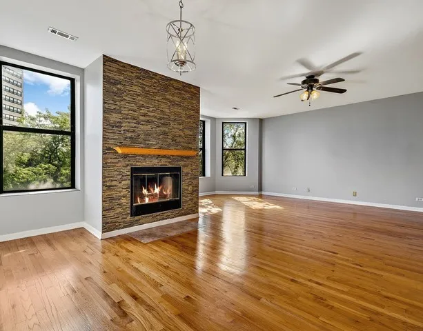 an empty room with windows fireplace and wooden floor