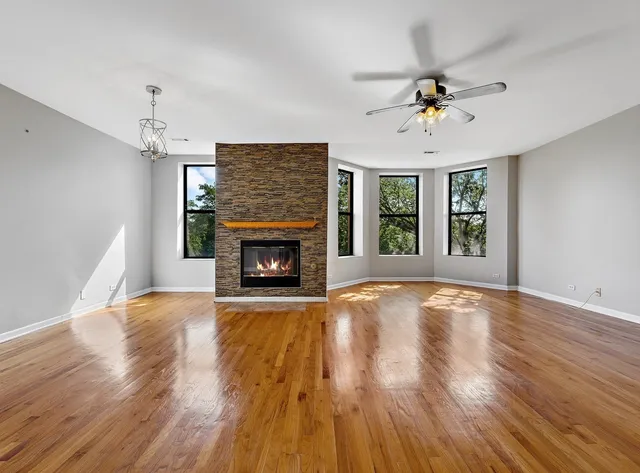 a view of an empty room with wooden floor fireplace and a window