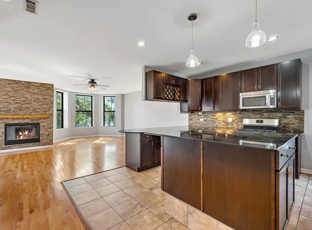 a kitchen with stainless steel appliances granite countertop a refrigerator a stove a sink dishwasher and a microwave with wooden floor