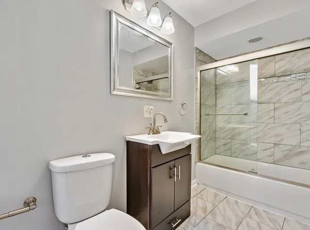 a bathroom with a granite countertop sink a toilet and bathtub