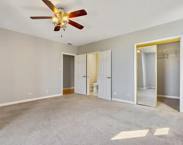 an empty room with closet and a chandelier fan
