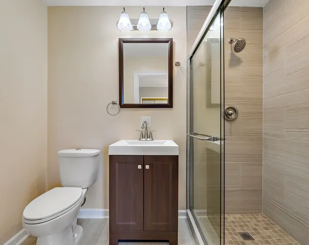 a bathroom with a toilet a sink a shower and mirror