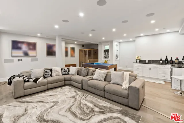 a living room with furniture kitchen area and large windows