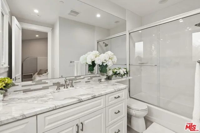 a bathroom with a granite countertop sink toilet and shower