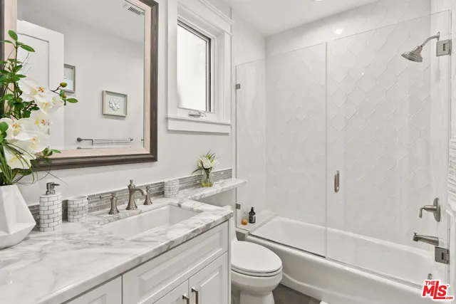 a bathroom with a granite countertop sink mirror toilet and bathtub