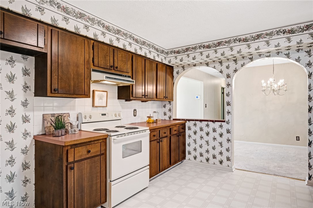 6452 Carsten Road Medina, OH 44256 - Photo 13 of 41 Kitchen featuring backsplash, white range with electric stovetop, light tile flooring, a notable chandelier, and hanging light fixtures