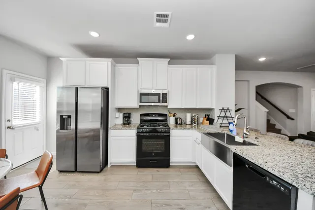 a large kitchen with stainless steel appliances granite countertop a refrigerator a stove a sink and a microwave