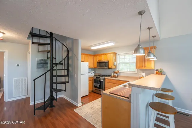 a kitchen with stainless steel appliances granite countertop a refrigerator a stove and a wooden floors