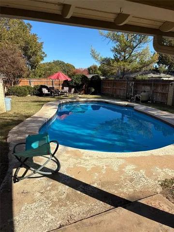 a view of swimming pool with seating area and trees in the background
