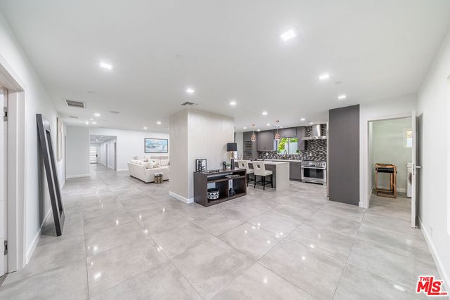 a kitchen with stainless steel appliances a stove a sink a oven a dining table and chairs