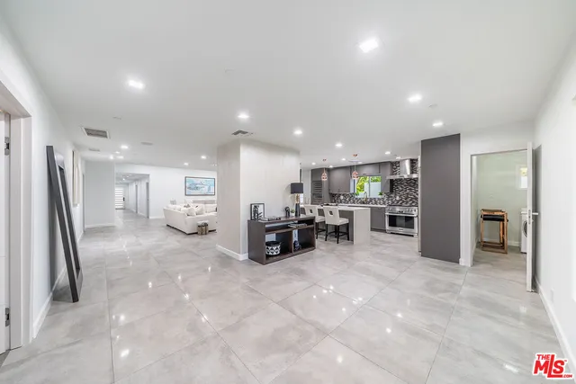 a kitchen with stainless steel appliances a stove a sink a oven a dining table and chairs