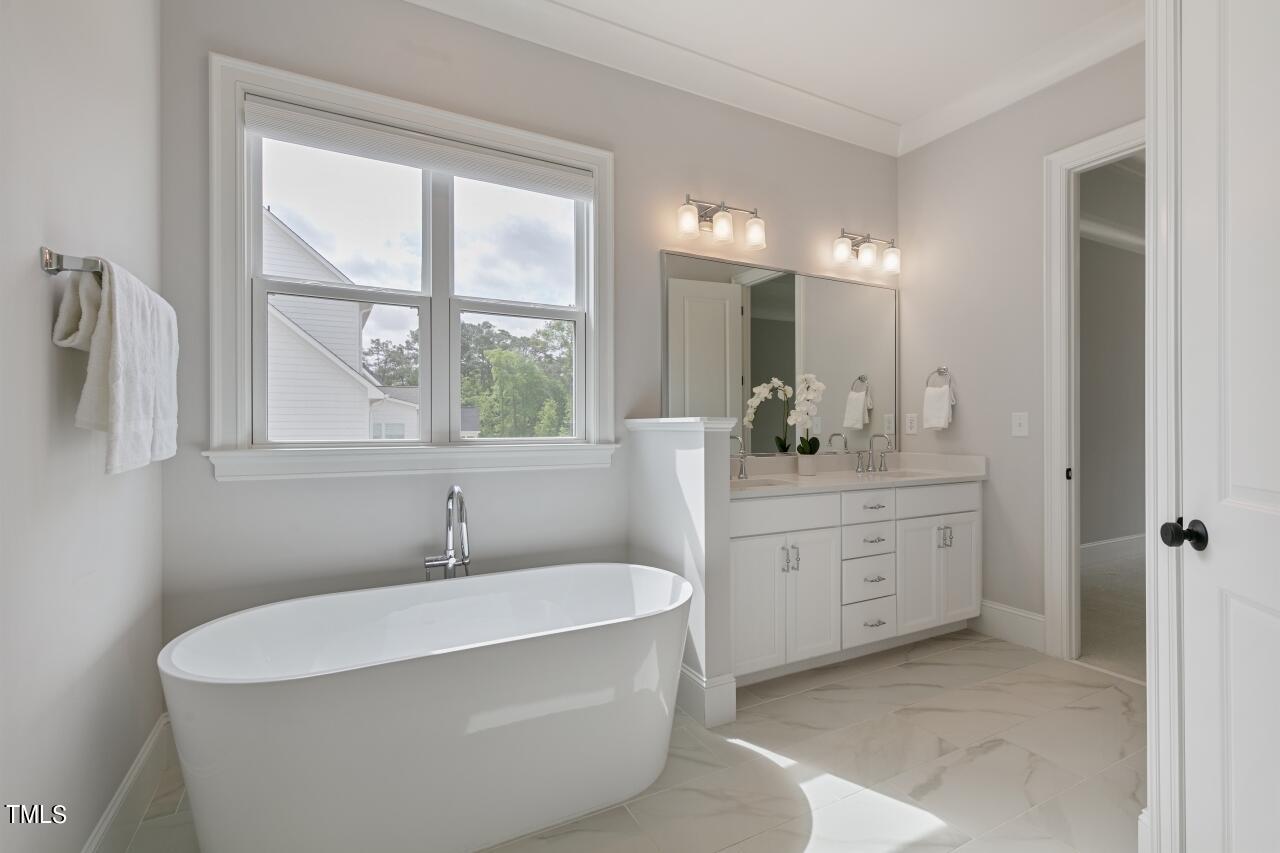 816 Crimson Rdg Trail Fuquay-Varina, NC 27526 - Photo 20 of 42 a bathroom with a double vanity sink a mirror and a bathtub