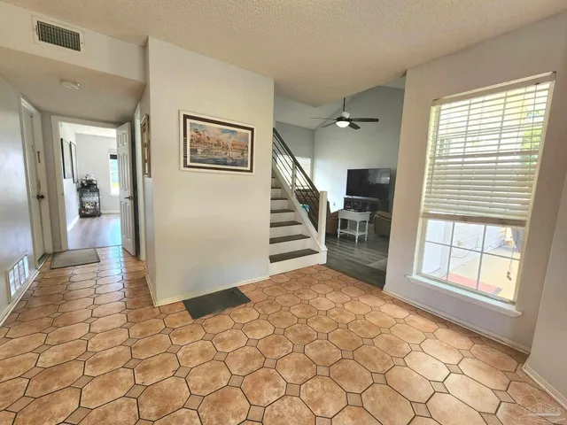 a view of a hallway with windows and stairs with wooden floor