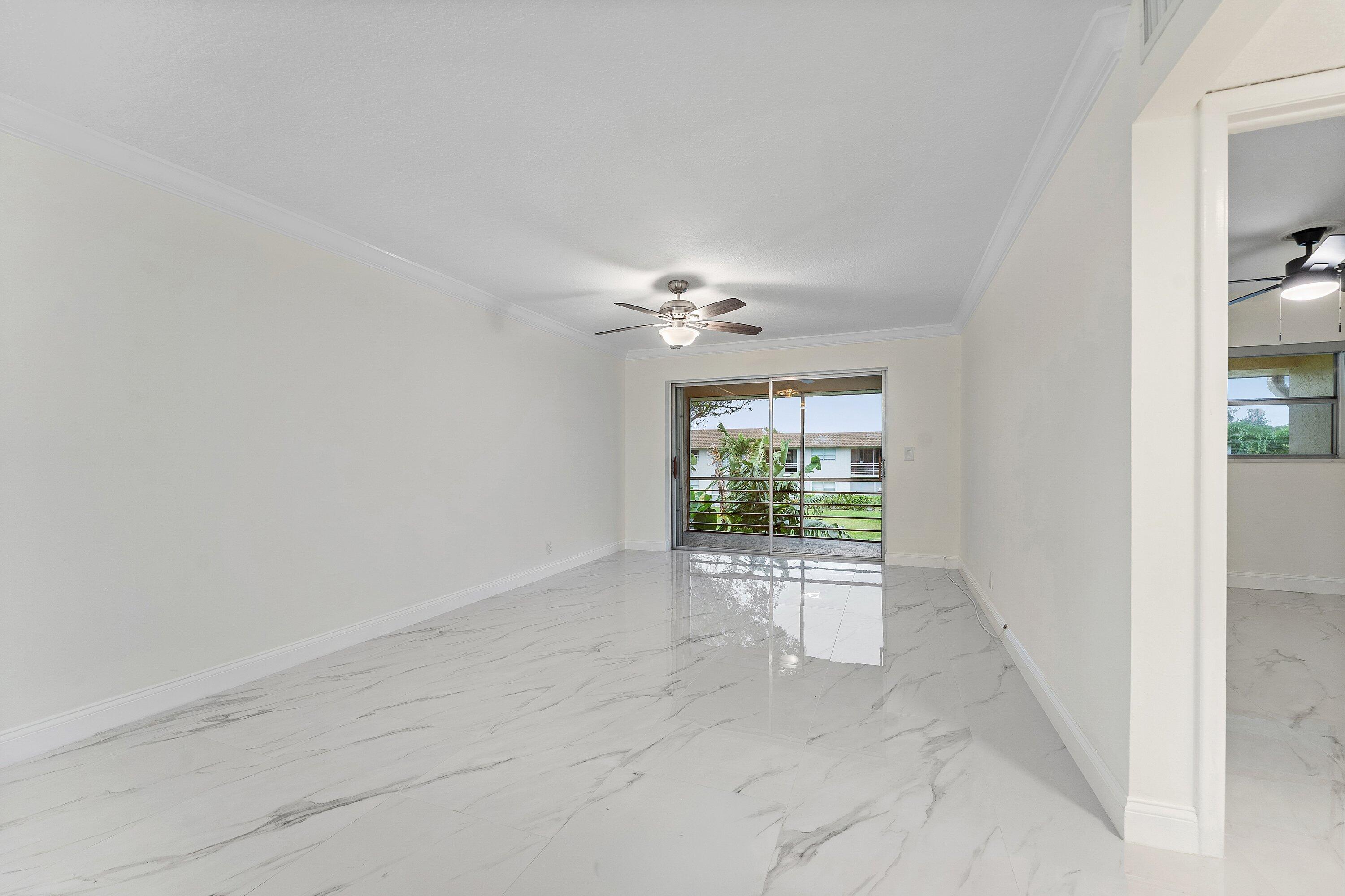 9911 Sandalfoot Boulevard, Unit 113 Boca Raton, FL 33428 - Photo 15 of 19 an empty room with windows and ceiling fan