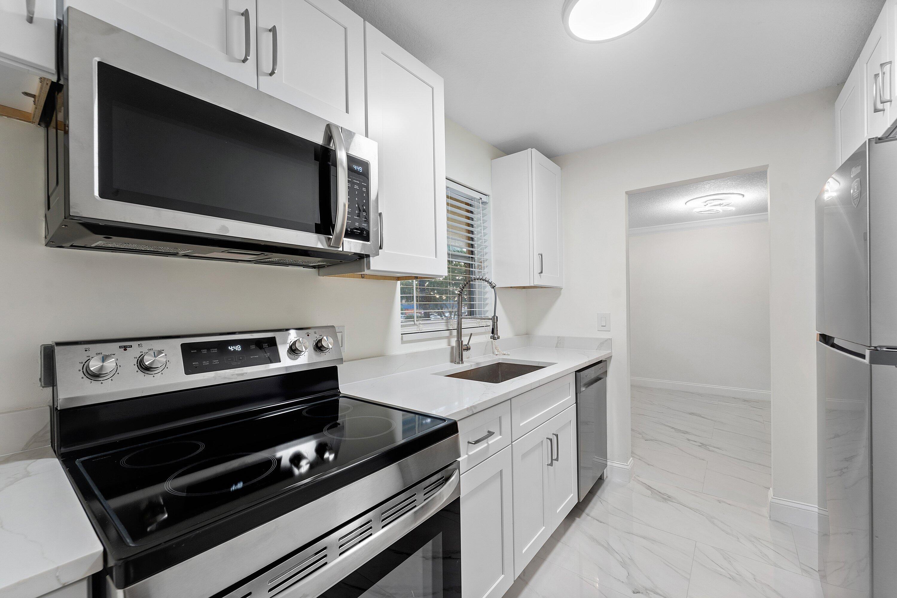 9911 Sandalfoot Boulevard, Unit 113 Boca Raton, FL 33428 - Photo 16 of 19 a kitchen with a sink stove and microwave