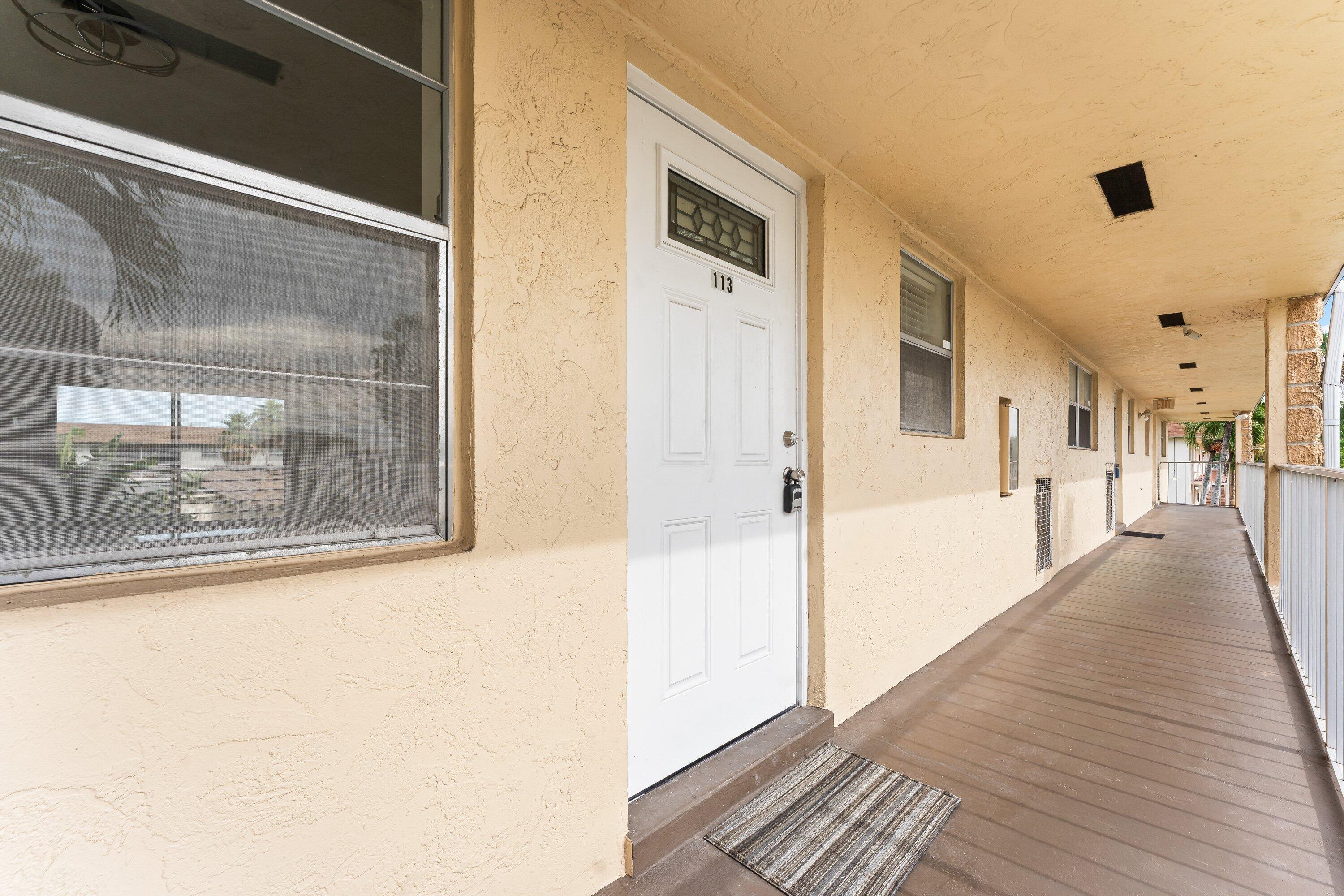 9911 Sandalfoot Boulevard, Unit 113 Boca Raton, FL 33428 - Photo 2 of 19 a view of a hallway with wooden floor and a living room