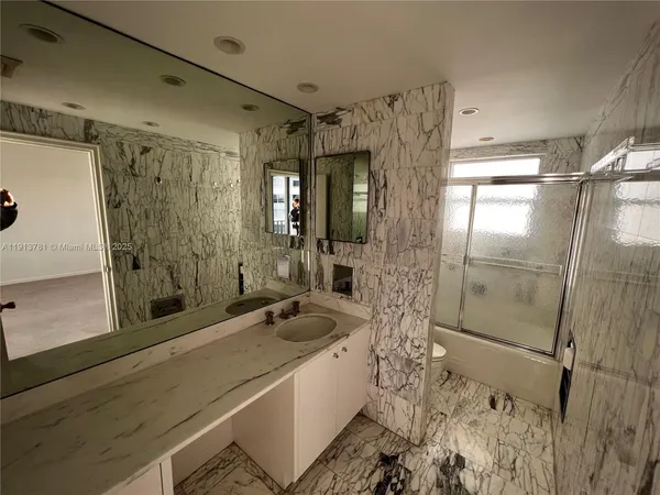 a bathroom with a double vanity sink a toilet a mirror and shower