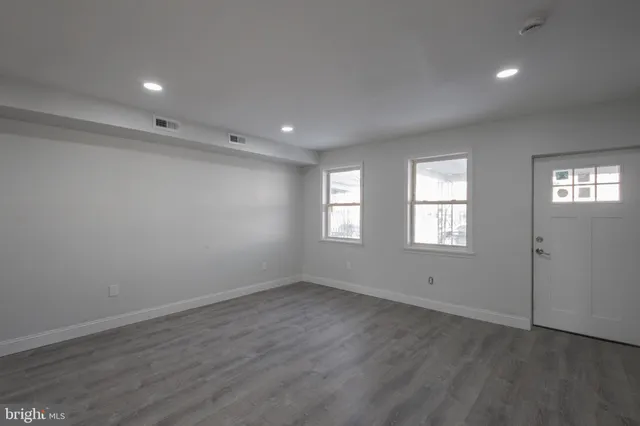 an empty room with wooden floor and windows