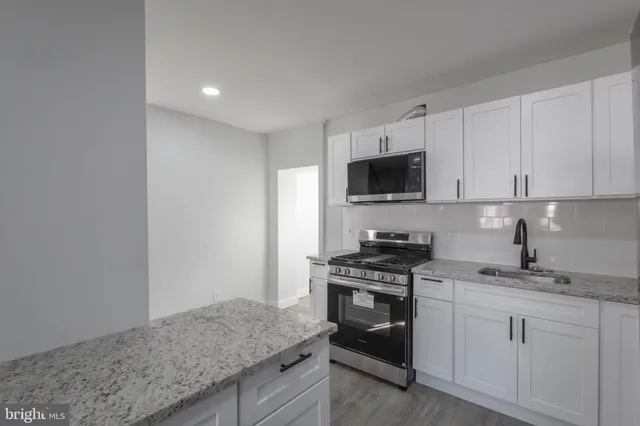 a kitchen with granite countertop white cabinets stainless steel appliances and a sink