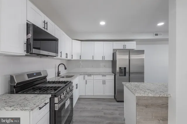 a kitchen with stainless steel appliances granite countertop a stove top oven a sink dishwasher and a refrigerator with wooden cabinets