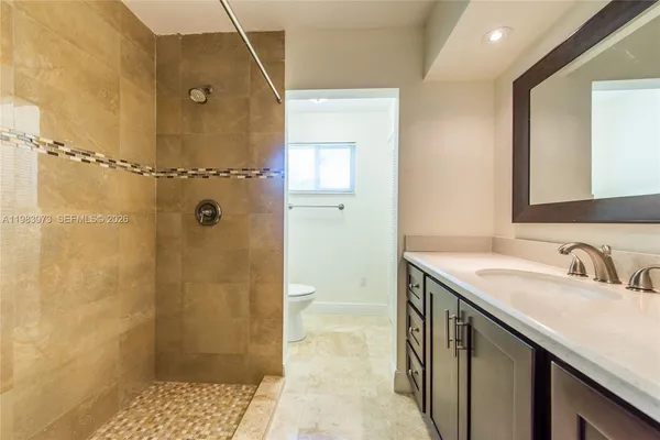 a bathroom with a granite countertop sink a mirror and shower