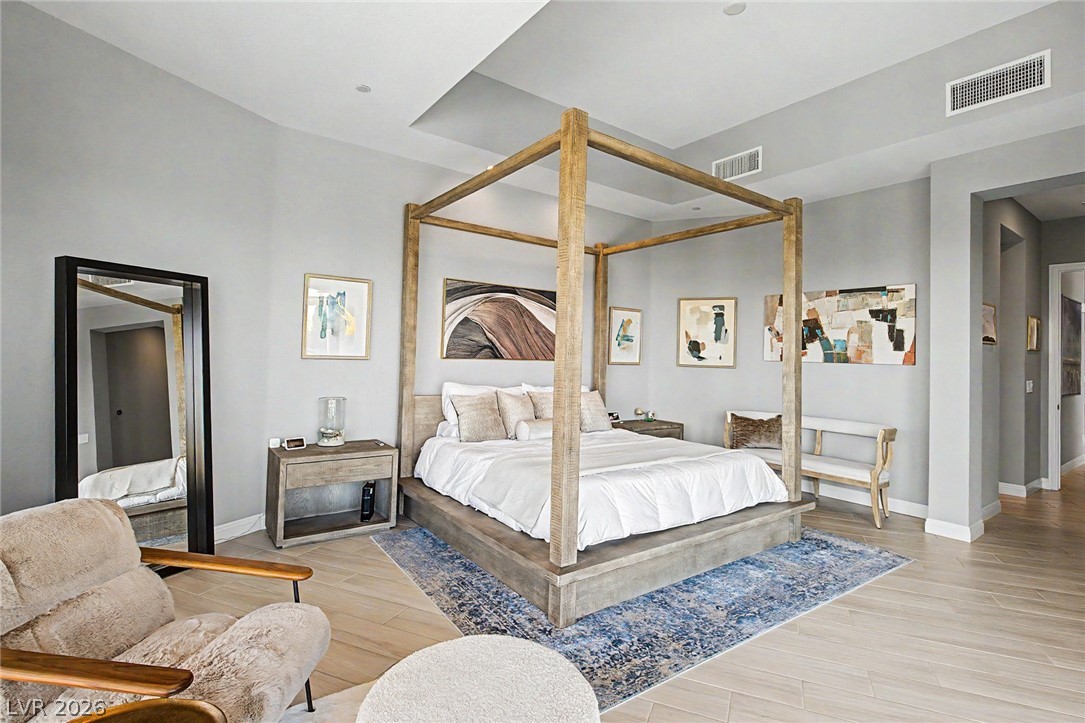 6014 Willow Ridge Court Las Vegas, NV 89135 - Photo 40 of 99 This spacious bedroom features a distinctive tray ceiling and light wood-look flooring.
