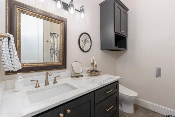 a bathroom with a granite countertop sink a toilet and a mirror