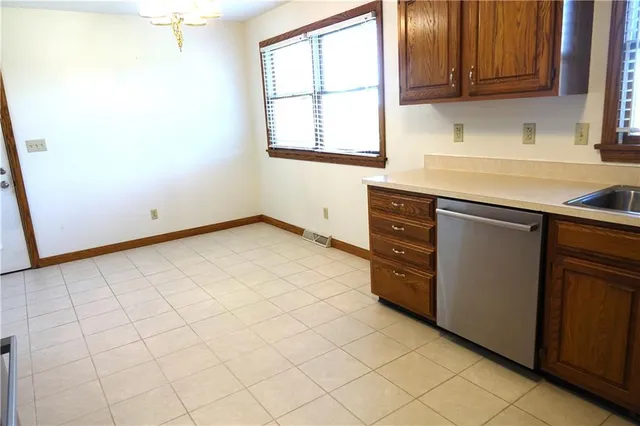 a view of a refrigerator in kitchen and an empty room