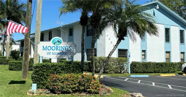 a front view of a multi story residential apartment building with yard and sign board