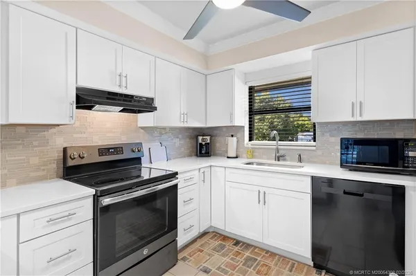 a kitchen with cabinets stainless steel appliances a sink dishwasher and a stove with wooden floor