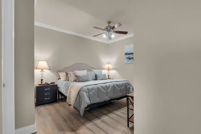 a bedroom with a bed ceiling fan and a wooden floor