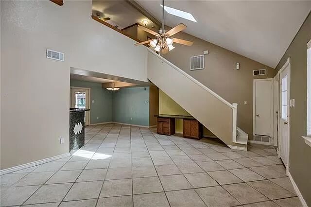 7801 Coldstream Drive Austin, TX 78748 - Photo 6 of 20 Unfurnished living room featuring light tile patterned floors, stairway, high vaulted ceiling, a ceiling fan, and a skylight