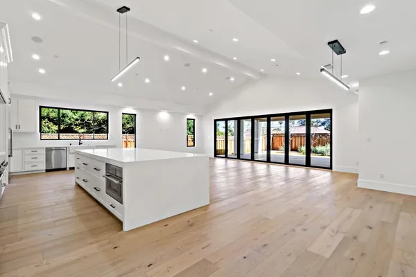 a large kitchen with stainless steel appliances a large counter top and a wooden floor