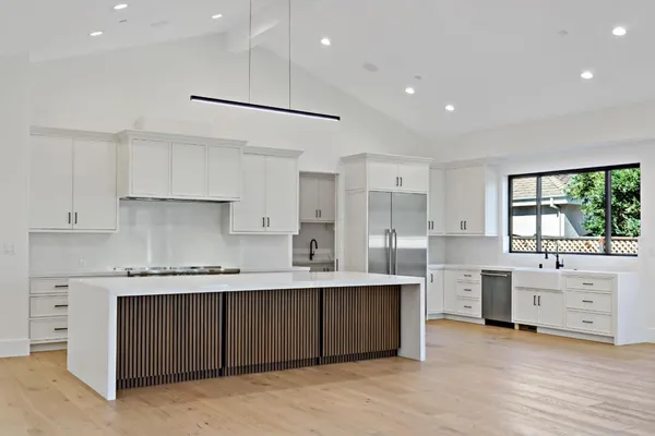 a kitchen with stainless steel appliances kitchen island granite countertop a stove a sink and white cabinets with wooden floor