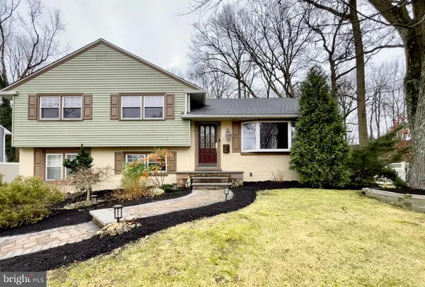 a front view of a house with yard and trees around