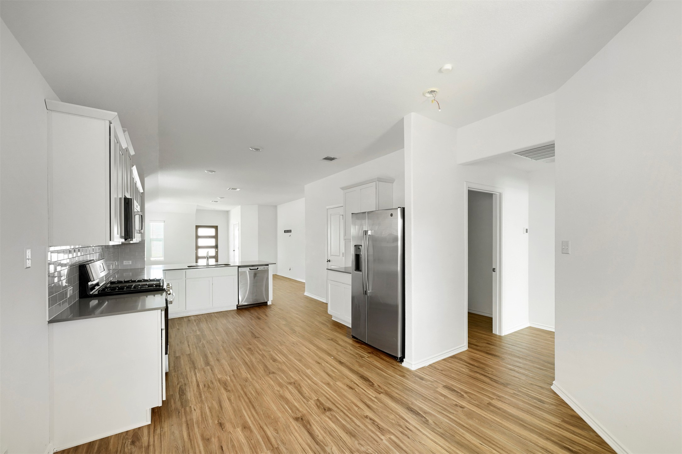 120 Milliner Loop Hutto, TX 78634 - Photo 5 of 15 A well-lit, open-concept kitchen features sleek appliances and wood flooring.