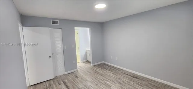 a view of hallway with closet and wooden floor