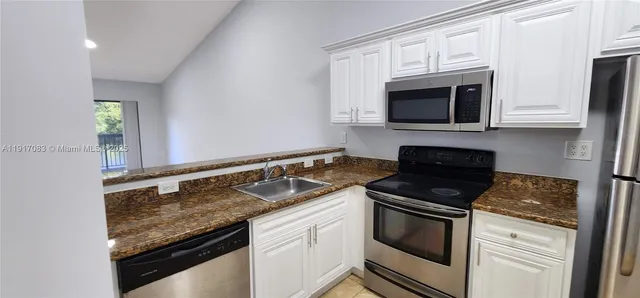 a kitchen with granite countertop white cabinets and appliances