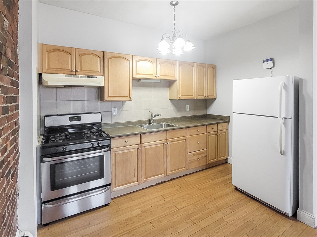 338-342 Warren Street, Unit 1 Boston, MA 02119 - Photo 3 of 10 a kitchen with granite countertop white cabinets and white appliances
