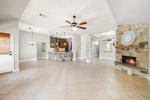 a view of a livingroom with a fireplace a chandelier and windows