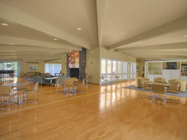 a living room with couches and kitchen view with wooden floor
