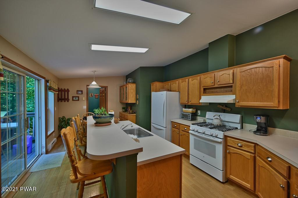 417 Northgate Road Lake Ariel, PA 18436 - Photo 17 of 91 a kitchen with stainless steel appliances granite countertop a stove a refrigerator a sink dishwasher a dining table and chairs with wooden floor