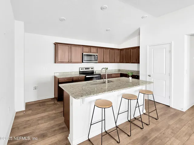 a kitchen with granite countertop a stove a sink and a refrigerator