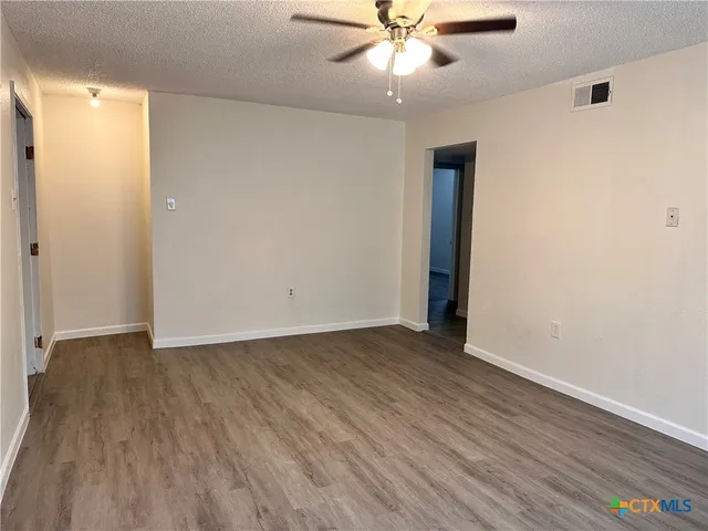 an empty room with wooden floor chandelier fan and closet area