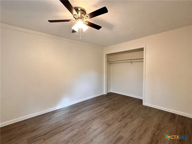 an empty room with wooden floor and a ceiling fan