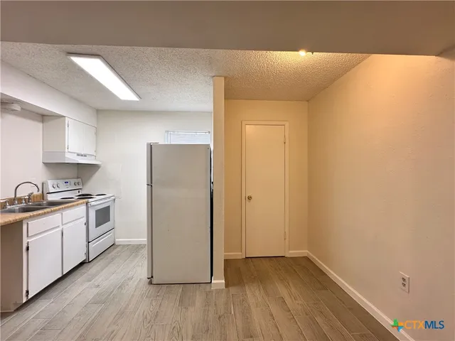 a kitchen with a refrigerator a sink and wooden floor