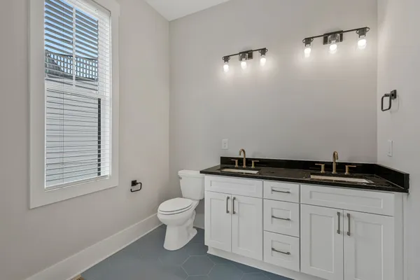 a spacious bathroom with a granite countertop sink a toilet and a mirror
